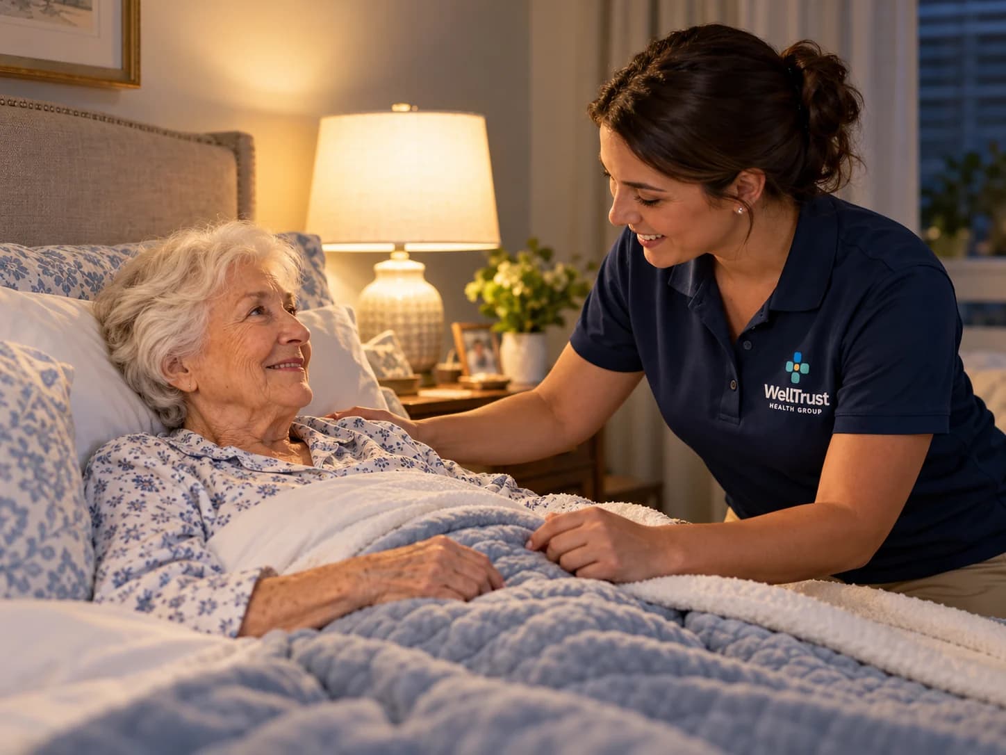A WellTrust companion checking in on an older woman resting in bed in the evening