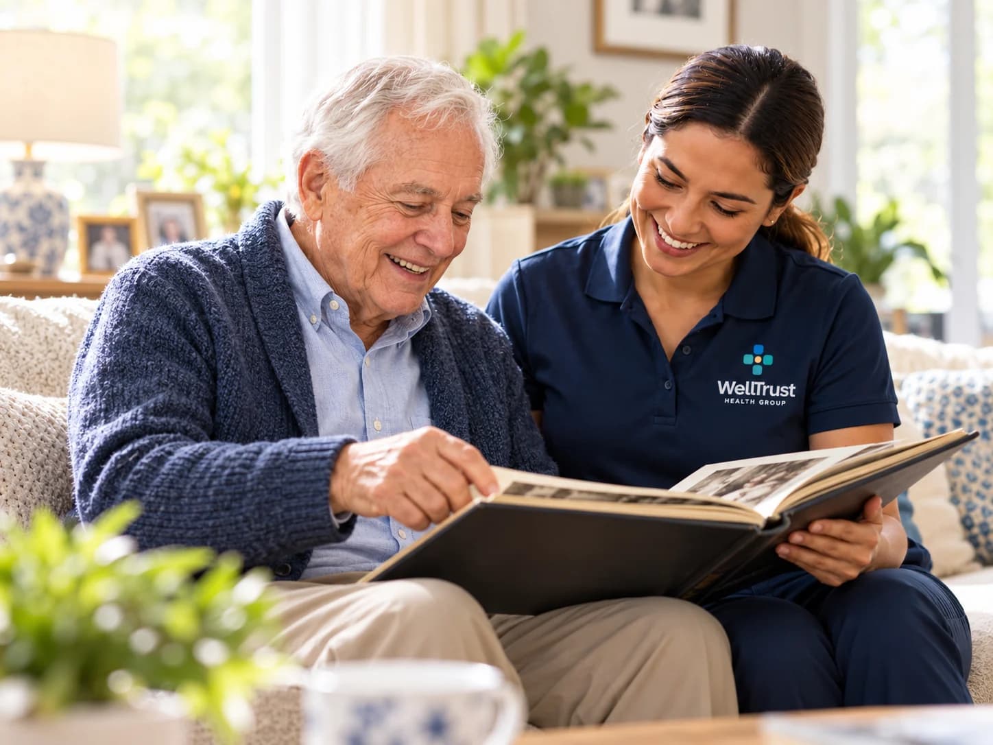 An older man sharing his photo album with a WellTrust companion on the sofa