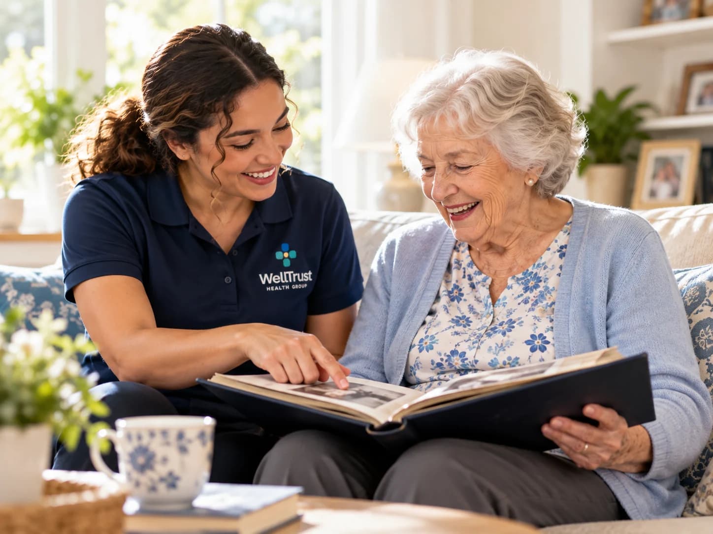 A WellTrust companion and an older woman laughing together over a family photo album